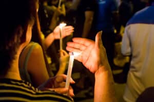 community in mourning holding lit candlesticks