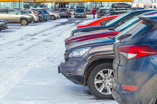 Rows of cars in a packed parking lot with snow on the ground.
